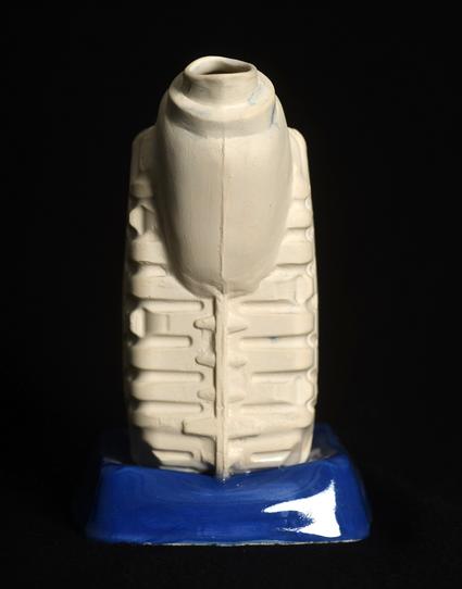 A slip casted ceramic pitcher that looks like pieces of plastic container put together. The main body part, the handle and spout are unglazed white stoneware, the base is a glossy blue upside down ceramic imitation of another plastic container.
