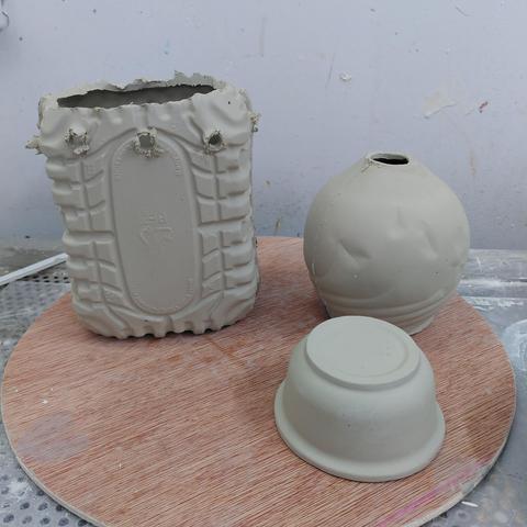 Greenware of slip cast ceramic of parts of the plastic container pitcher before being put together.