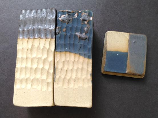 Glaze tests of a metallic glaze and a black matte glaze on textured test tiles and flat test tiles