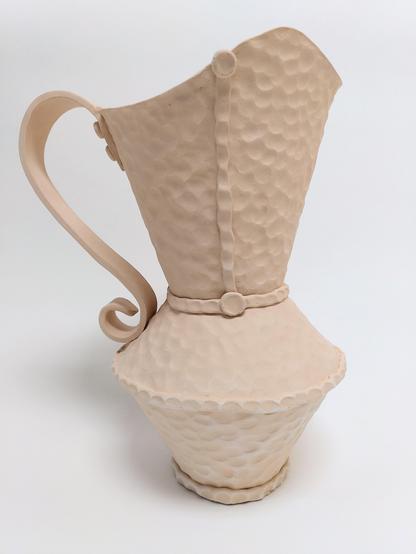 Bisque fired handbuilt pitcher. Handbuilt. It has a hammered like texture like we can find on hammered copper objects. it is built out of 3 conical parts. 2 cones are creating the body and the third creates a large spout opening. big flat handle.