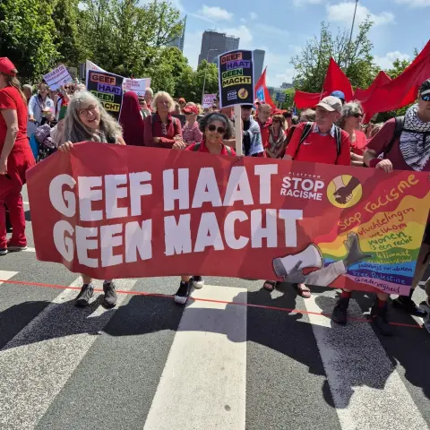 Mensen tijdens de demonstratie de Rode Lijn op 15 juni 2025 met een spandoek van GEEF HAAT GEEN MACHT van PLATFORM STOP RACISME