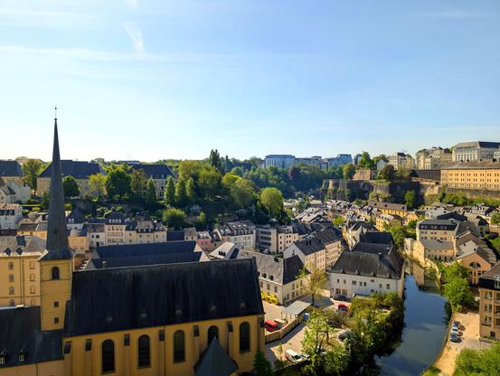 The Grund quarter in central Luxembourg City on warm and sunny day. Neimënster Abbey on the banks of the Alzette river and parts of the National Archives of Luxembourg can be seen partially.