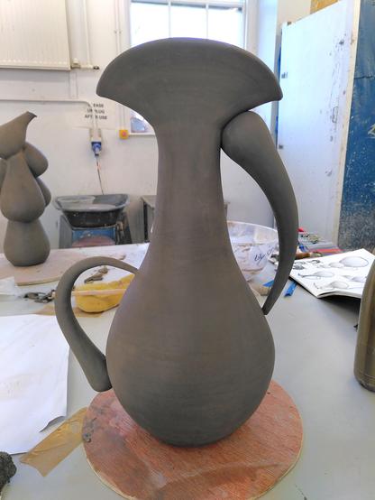 Medium ceramic water drop pitcher at the greenware stage. The body is a water drop shape and the 2 handles are arched elongated drops as well.