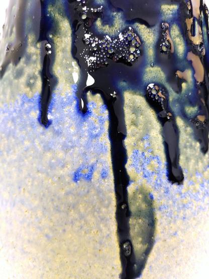 Ceramic glaze detail. White satin base with drippy and bubbly blue glaze. when they both meet there are tons of little blue crystals forming.