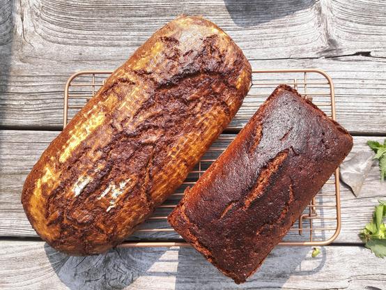 Zwei sehr stark glänzende Laibe Brot, einer freigeschoben, einer als Kasten.