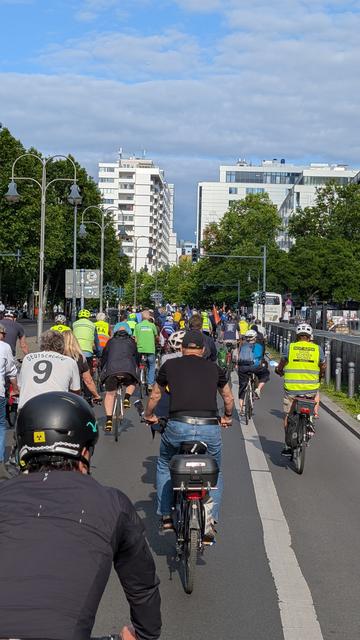 Die Fahrradkundgebung fährt durch die Straßen. Ein Teilnehmender hat eine Weste um: Bitte nicht hupen. Suche sicheren Radweg. Changing Cities.