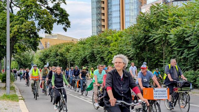 Viele Menschen fahren gemeinsam Fahrrad. Auf einem Fahrrad ist ein Protestschild gegen den Abbau der Radwege in der Kantstraße angebracht.