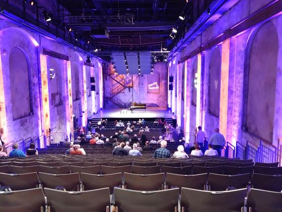 Industrial hall with blue lighting and a stage with a grand piano