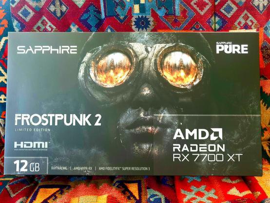 Box of the SAPPHIRE PURE AMD Radeon RX 7700 XT 12GB Frostpunk 2 Edition - guy's got dual monocles!