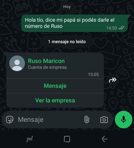 La imagen muestra una captura de pantalla de una conversación en WhatsApp. En la parte superior, se ve un mensaje de texto en español que dice: "Hola tío, dice mi papá si podés darle el número de Russo". Este mensaje fue enviado a las 14:50 y tiene una marca de verificación verde, indicando que fue leído. Debajo del mensaje, se muestra una notificación que indica "1 mensaje no leído".

En el centro de la imagen, hay una ventana emergente que muestra un contacto llamado "Ruso Maricon" con la descripción "Cuenta de empresa". El mensaje de este contacto fue enviado a las 15:05. La ventana emergente ofrece dos opciones: "Mensaje" y "Ver la empresa".

En la parte inferior de la pantalla, se encuentra la barra de herramientas de WhatsApp, que incluye un campo de texto para escribir un mensaje, un icono de papel picado, un icono de cámara y un botón de micrófono verde para enviar un mensaje de voz. El fondo de la pantalla es oscuro con varios iconos y patrones en blanco, como corazones, corazones con ojos, y otros símbolos