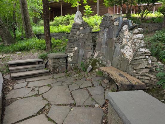 A stone pathway and staircase next to stonework surrounding a pond.