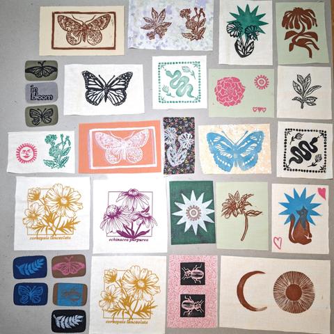 An image of 29 different fabric patches of various sizes and colors, with different designs printed onto them. There are butterflies, moths, snakes, flowers, beetles, suns, ferns, and a cat.