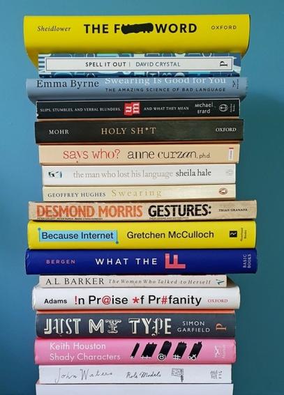 A stack of books against a blue background. They are arranged to form a visual poem, as written in the blog post. Their varied designs and colourful spines and typefaces – in yellows, blues, orange, black, whites and off-whites – lend visual interest.