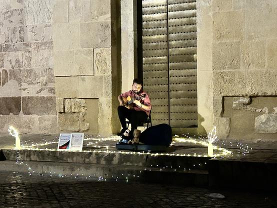 A guitarist surrounded by candles plays at one of the doors to the mezquita