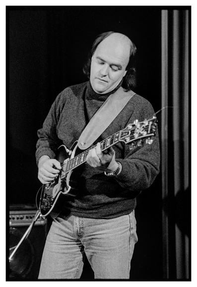 Black and white photograph of Peter John O'Mara playing the guitar.