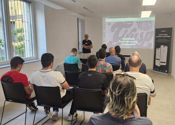 Foto della sala del meetup, con 3 file di sedie occupate ed Enrico Zimuel in piedi affianco al sito del Grusp proiettato