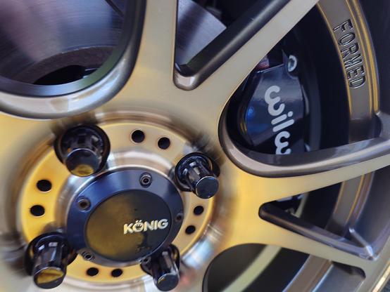 Close up of Wilwood calipers behind shiny bronze wheels