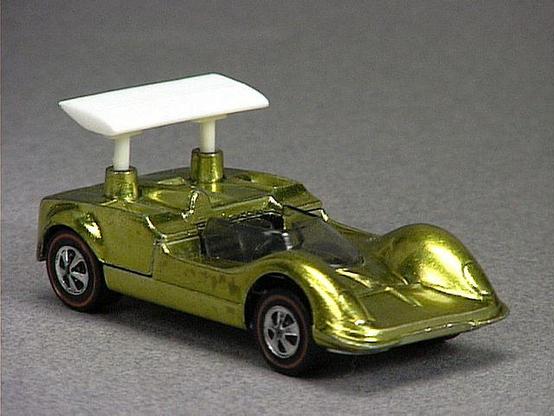 Released in 1969, Spectraflame Gold Chapparal 2G of 1969 Grand Prix with Redline wheels. Notes: Car has white plastic spoilers. HK casting has longer exhaust headers. Packaging: Grand Prix. Metal Body, Metal Base. Made in Hong Kong. Scarcity: 3/10