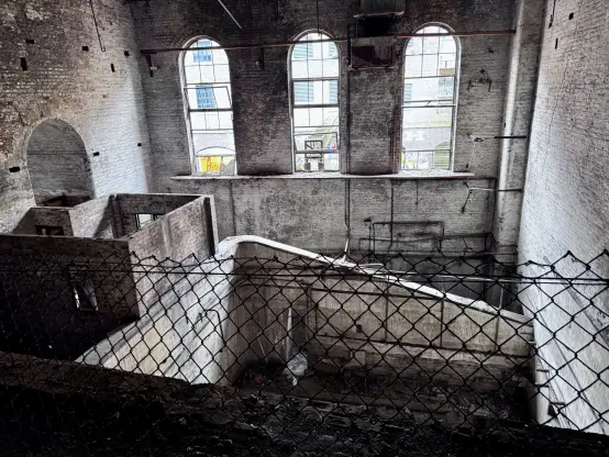 A large structure to the right, that goes a floor lower and contained some sort of machinery before. There’s significant amounts of sunlight in the space due to the windows in the background