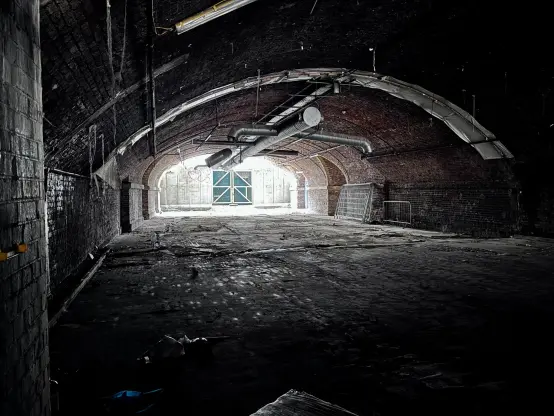 A large space underneath one of the arches, with multiple utilities hanging from the ceiling.