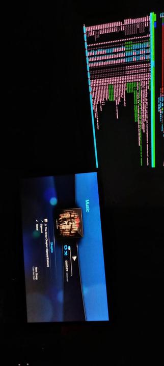 The photograph composed in total darkness shows two screens with different content. The top screen displays a colorful, text-based interface with multiple lines of text in various colors, including pink, green, blue, and white, against a black background. The text appears to be a log or data stream, with some sections highlighted in different colors, possibly indicating different categories or statuses.

The bottom screen shows a music player interface with a blue background. The interface displays the album cover of "Spectral Moods" by "Spectral," with the text "Music" on the right side. The player shows the current song as "St. The Gray - Chapter Special Edition," with a progress bar indicating the song is at 00:00:21 out of 00:05:18. The screen also shows options for "Next Song" and "Current Song."

 Ovis2-8B

🌱 Energy used: 0.207 Wh