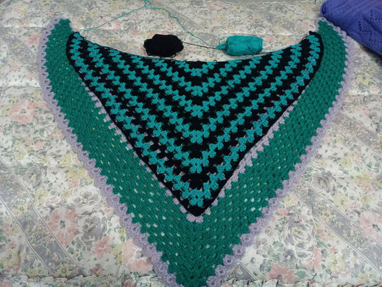 Emochal, con franjas en V alternas verde azulado y negras, sobre Protochal, principalmente verde y con dos franjas en V y el remate en lila. Emochal casi cubre por completo la segunda franja de Protochal.
Sobre ambos están los dos ovillos que estoy usando, cada vez más raquíticos.