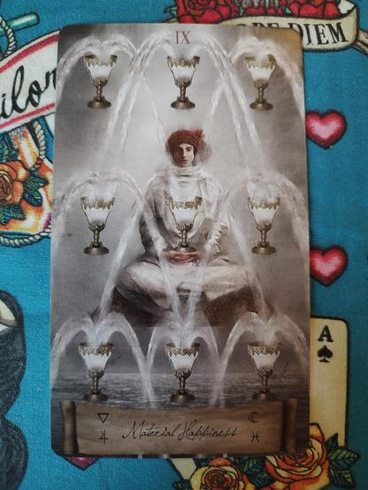 Card from the Heaven and Earth Tarot deck. 
Nine of Cups.
A man dressed in white wearing a red turban sits cross legged, facing the viewer. Around and in front of him nine cups spouting water like fountains.