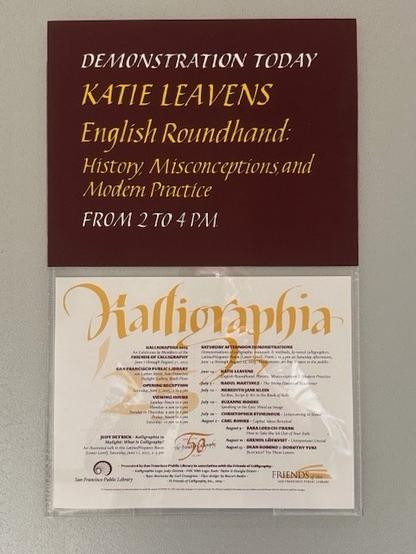 A wall display announcing a demonstration by Katie Leavens on "English Roundhand: History, Misconceptions, and Modern Practice," scheduled from 2 to 4 PM. Below is a flyer titled “Kalligraphia ’25,” listing related events and presentations