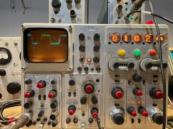 An oscilloscope with a nixie tube read out showing the period of a signal on screen, marked by an intensified zone.