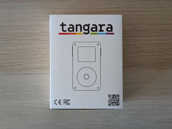 A photo of the media player's box. Visible is a diagram of the device, the name tangara underlined with a rainbow line, CE and FCC markers, and a QR code.