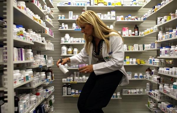 A pharmacy manager retrieves a bottle of antibiotics. (Photo by Joe Raedle/Getty Images)