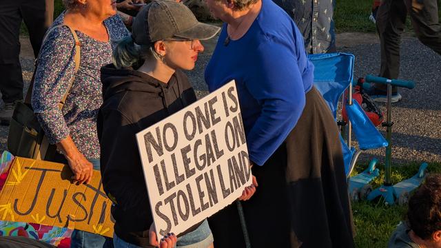 Woman holding sign "no one is illegal on stolen land"