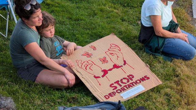 Mother and son sitting and listening, with sign of handcuffed hands, monarch butterflies, and text "Stop deportations"