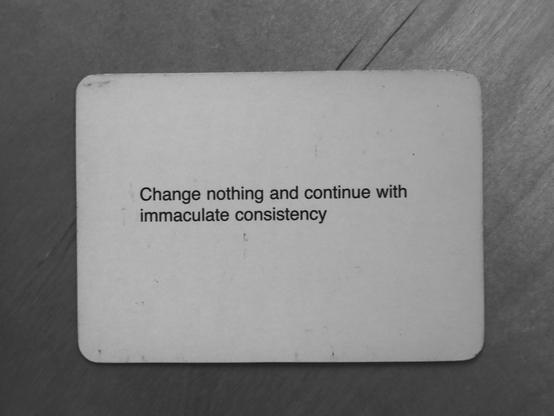 A black-and-white photo of an Oblique Strategy card. The card reads: 'Change nothing and continue with immaculate consistency'.
