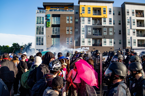 After police begin deploying tear gas on peaceful protesters, the protestors throw tear gas canisters behind police lines.