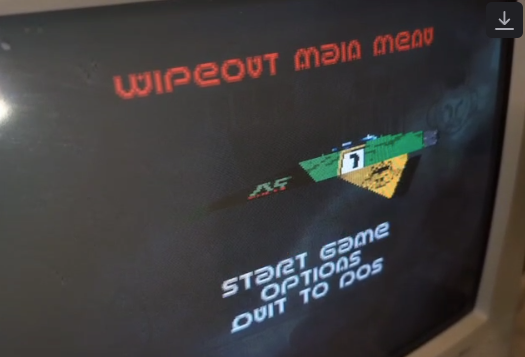 CRT showing the title screen for wipeout in the main menu. We see a futuristic triangle shaped racing vehicle, with the menu items Start Game, Options and Quit to DOS