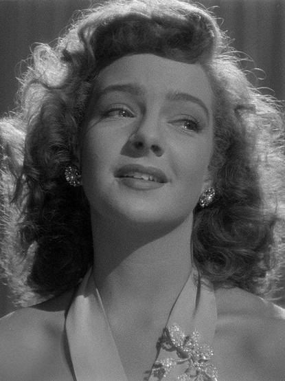 Retrato en blanco y negro de Martha Roth con una expresión melancólica, lleva un vestido con detalles brillantes.