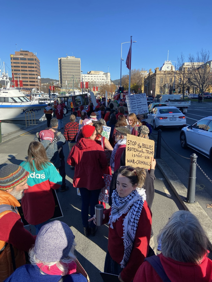 a pro-Palestine rally in Lutruwita. people wear red to symbolise the “red line” and hold banners towards the parallel traffic