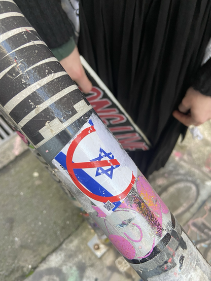 a anti-israel sticker on a hand rail. the sticker has been slightly torn on one end