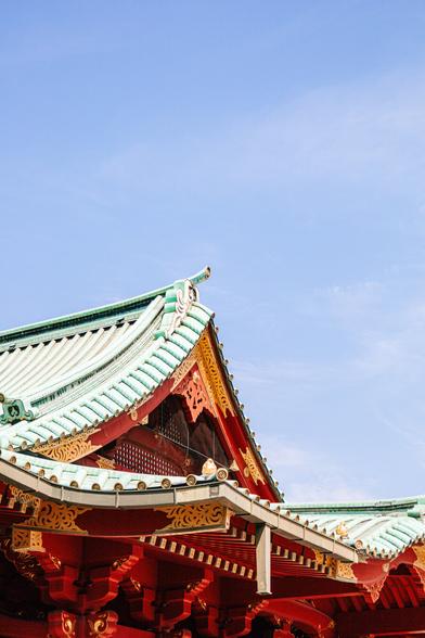A picturesque view of a traditional Japanese temple roof under a clear blue sky