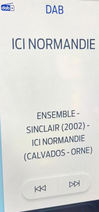 Close up of car radio display showing DAB+ logo, and name of broadcasting station: ICI Normandie.