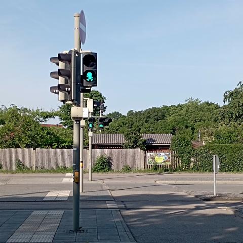 Pumuckl-Ampel an der H Stadtwerke München mit Blick auf Kleingartenanlagen im Hintergrund.