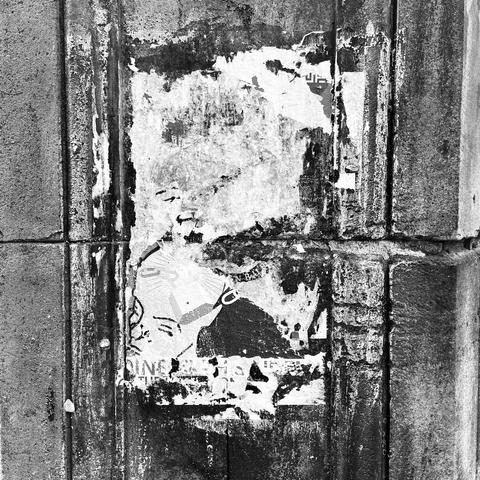 A similar photo, but with a distinct horizontal course between the stone blocks cutting across the middle, with torn remains of another poster.