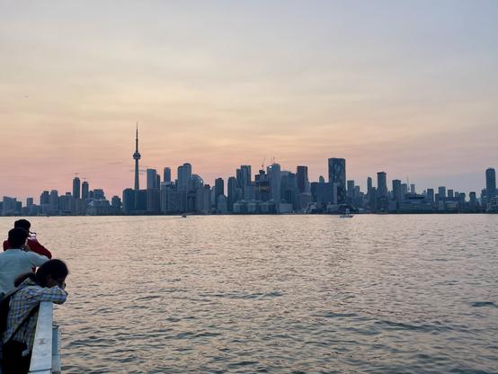 The picture shows a view of the Toronto downtown at dusk, seen from the ferry pier on the Toronto Islands.