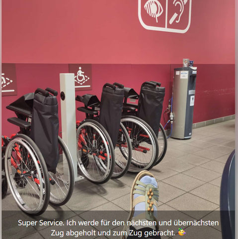 Blick über einen hochgelagerten, mit Schienen am Unterschenkel fixierten Fuß auf mehrere identische (offenbar zum Bahnhof gehörende) Rollstühle vor einer roten Wand mit Symbolen für verschiedenen Behinderungen. 
Darunter Text "Super Service. Ich werde für en nächsten und den übernächsten Zug abgeholt und zum Zug gebracht. 🥳"