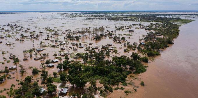 An aerial photo of the effects of Cyclone Idai in Mozambique, 2019. Brown floodwater is visible as far as the eye can see with occasional trees and buildings sticking out of the water.