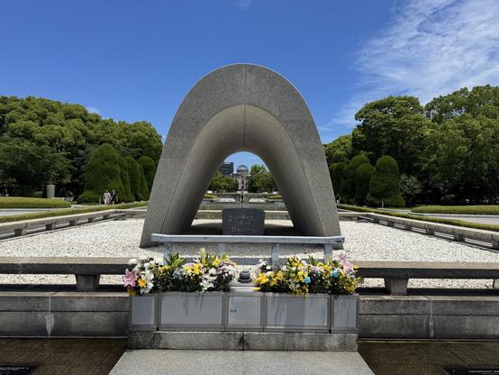 Concrete dome with a flame and domed building ruins in the background.