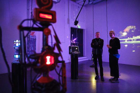 3 sculptures of Model Collapse with 2 visitors gazing at them.