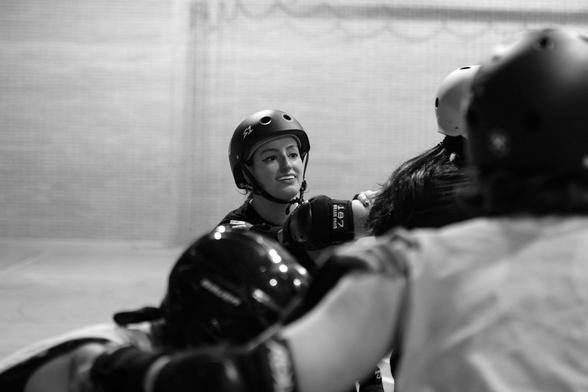 Foto en blanco y negro a punto de empezar a jugar. Algunas jugadoras están en posición y mirando hacia mí, no se les ve la cara, y en medio salgo yo, mirando al fondo del pabellón, con cara de no tener claro cómo voy a sobrevivir los próximos dos minutos.