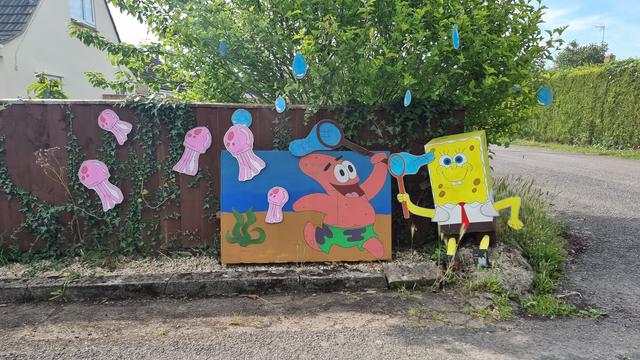Scene showing Spongebob Squarepants and Patrick, constructed from boxes, along the edge of a fence.